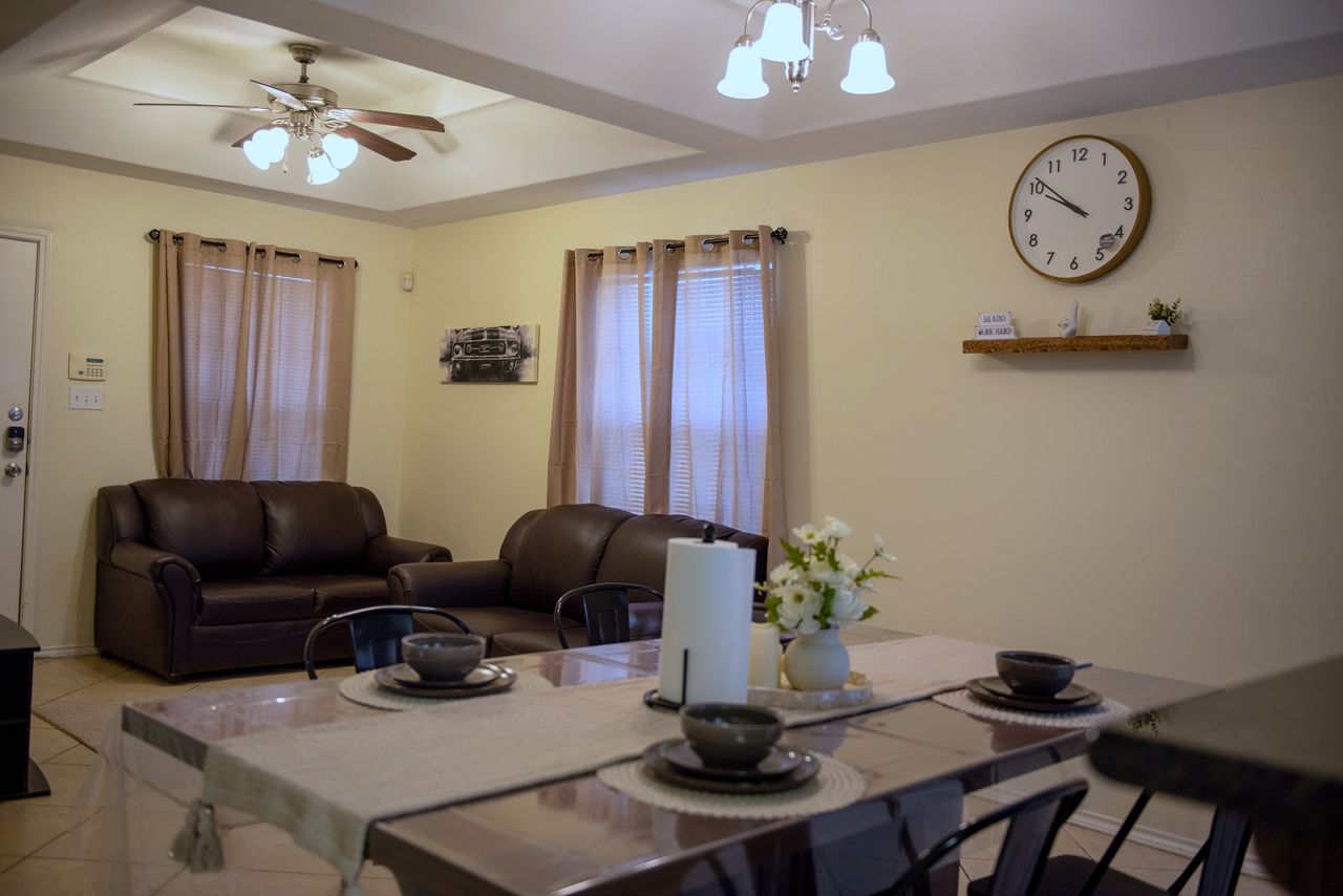 Open living and dining area with two leather sofas and a table set for four